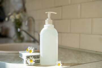 Fototapeta na wymiar Eco friendly non-toxic cleaning dish soap with chamomile flowers, clean white plates 