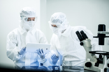 Middle shot of female Caucasian scientists analyzing results of microscope research, on the digital...