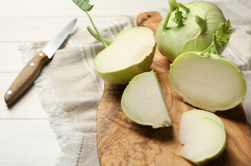 Whole and cut kohlrabi plants on white wooden table