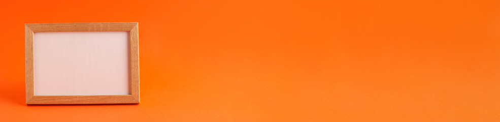 Fototapeta premium Close up banner of mockup template white frame with wooden borders on orange blurred background and copy space. Holiday autumn concept backdrop
