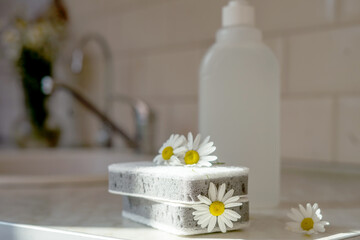 Fototapeta na wymiar Eco friendly non-toxic cleaning dish soap with chamomile flowers, clean white plates 