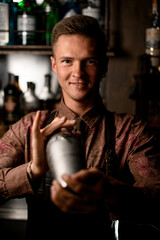 portrait of smiling man bartender holds a shaker in his hands and shakes it