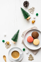 Fototapeta na wymiar Ein weihnachtlich gedeckter Tisch mit Macarons auf einem Teller und eine Tasse Kaffee. Kaffeepause, Dessert.