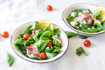 Fresh delicious salad with prosciutto, baby spinach, blue cheese and cherry tomatoes in vintage salad bowl, closeup. Italian style cuisine..