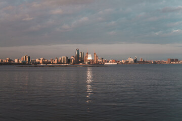 Naklejka premium Embankment of Baku at sunset. Sunset sky in Baku, Azerbaijan. Golden light on the skyscrapers. High quality photo