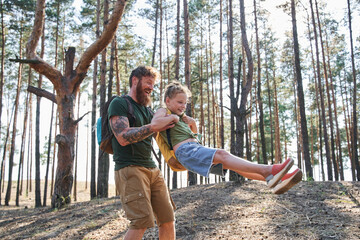 Fototapeta premium Man spinning his daughter in arms in forest