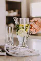 Male hand taking transparent jug with citrus mint limonade.