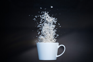 Blank white ceramic mug on black background with coconut flakes and glitter