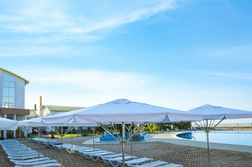 Beach umbrellas and sunbeds near outdoor swimming pool at resort