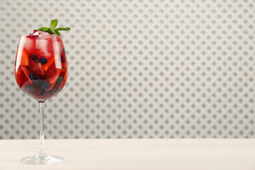 Glass of Red Sangria with fruits on white wooden table, space for text