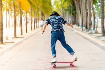 A young Asian man in a striped shirt and trousers is figure skating on a beach filled with coconut...