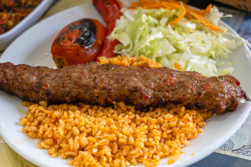 Adana Kebab, traditional Turkish cuisine with kebab meat, vegetables on the plate