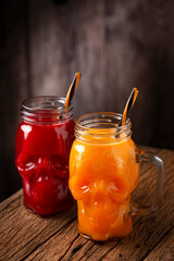 Halloween drink. Pumpkin drink and blood drink in skull glass.