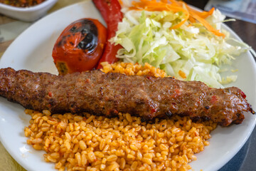 Adana Kebab, traditional Turkish cuisine with kebab meat, vegetables on the plate