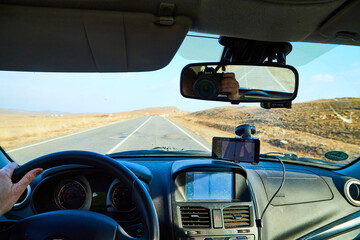Siberia Baikal, Russia - November 20, 2020: View from of car interior from side of driver to the road and autumn yellow nature landscape with hills through the windshield