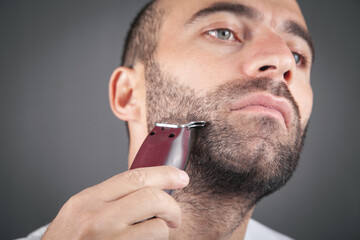 Caucasian man shaving with electric trimmer. - obrazy, fototapety, plakaty