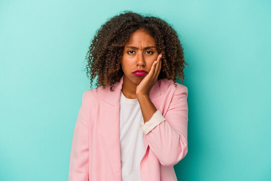 Young african american woman with curly hair isolated on blue background who feels sad and pensive, looking at copy space.