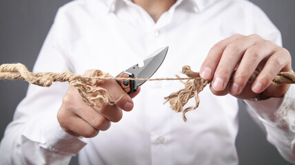 Man with knife cutting frayed rope. Risk