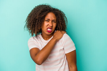 Young african american woman with curly hair isolated on blue background having a shoulder pain.