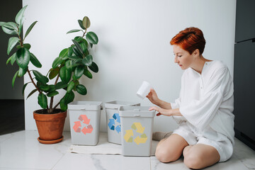 Concerned woman sorting garbage beween small recycle bins at home