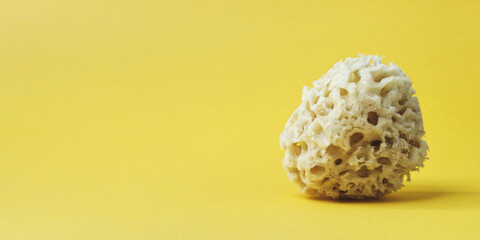 Natural bath sponge on yellow background with copy space...