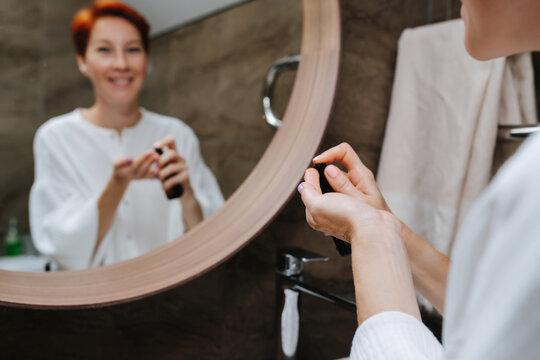 Blurred mirror image of a mature woman putting cosmetics on her hand