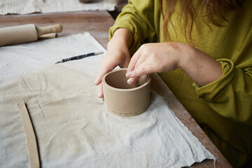 Fototapeta na wymiar Female ceramist working in pottery studio. Ceramist's Hands Dirty Of Clay. Process of creating pottery. Master ceramist works in her studio