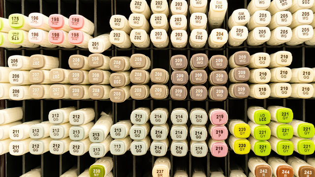 Professional alcohol markers are sold per piece at art stores for artists. Sketching markers are arranged by color on a shelf in an art supply store. Alcohol markers close-up background.