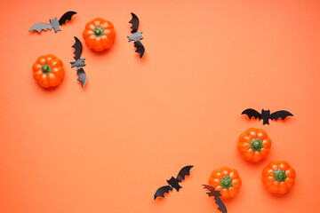 Halloween pumpkins and bats on orange background, space for text, flat lay. Halloween concept.