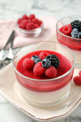 Delicious panna cotta with fruit coulis and fresh berries served on white marble table