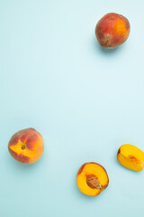 Fresh juicy peaches with leaves on bright blue background with copy space for your text. Top view. Flat lay pattern. Food composition