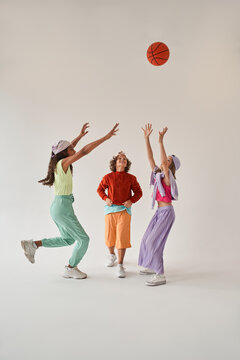 Kids standing isolated over white background and having fun while playing basketball