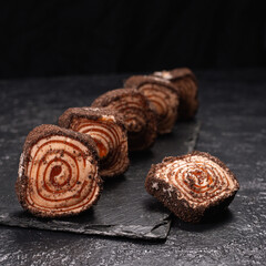 Sweet chocolate Turkish Delight placed in row on slate board on black background in studio. Traditional dessert of Ottoman cuisine   