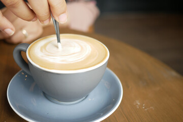 person hand stirring coffee with spoon.