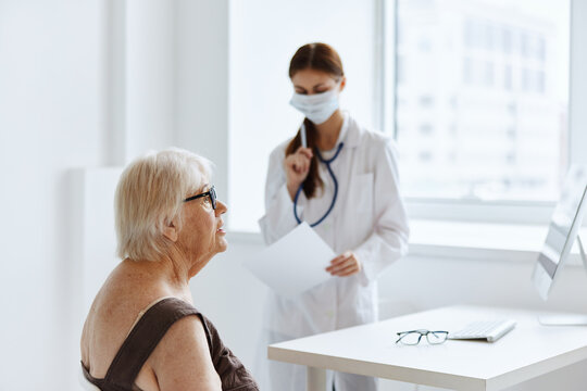 elderly woman wearing a medical mask communicates with the doctor health diagnostics