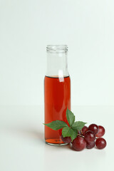 Bottle of vinegar and grape on white table