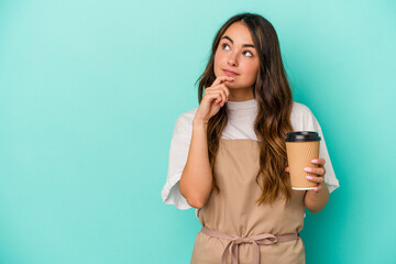 Young caucasian store clerk woman holding a takeaway coffee isolated on blue background looking...