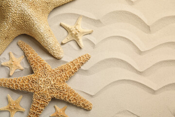 Beautiful sea stars on sand, flat lay. Space for text