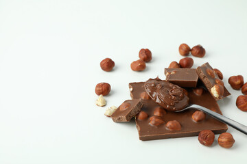 Spoon with chocolate paste and chocolate with nuts on white background