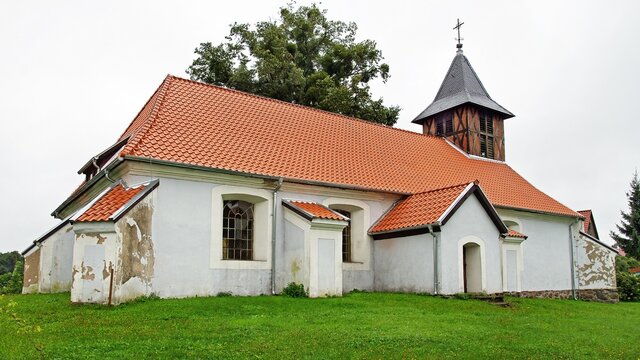 General view and architectural details of the Protestant church built in plastered red brick at the beginning of the 19th century in the village of Rańsk in Masuria, Poland.