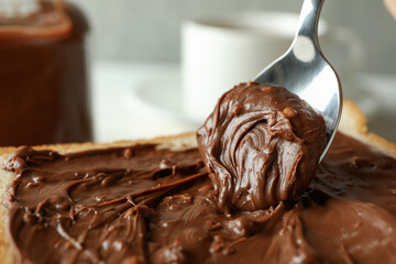 Spoon and bread with chocolate paste, close up and selective focus