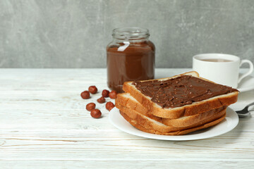 Concept of tasty breakfast with chocolate paste on white wooden table