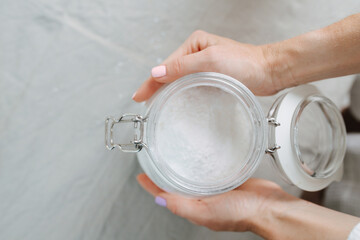 Top view of female hands holding glass jar with lid with white sugar like powder