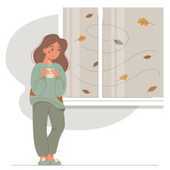 A sad girl in warm clothes stands by the window with a cup. Nice young woman warms her hands with a hot cup. Vector autumn mood illustration. 