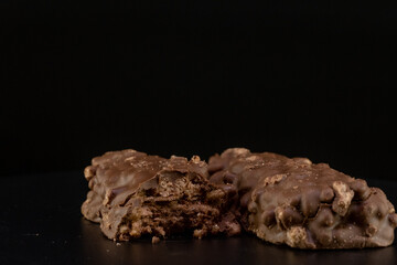 Soft bar crispy wafer with nuts and coated chocolate layer on black background