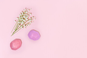Flowers of lilies of the valley and fragrant soap on soft pink background with free space for text. Handmade soap bars. Aromatherapy, beauty spa background. Top view.