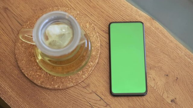 Smartphone place on table wood with green screen, Close-up the cell phone is on the brown table in the restaurant with chroma key, Green screen telephone, and top view