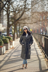 Elegant girl walk in a winter city. Woman in a white knited sweater. Beautiful lady with dark hair.