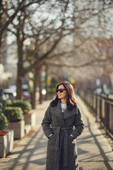 Fototapeta premium Elegant girl walk in a winter city. Woman in a white knited sweater. Beautiful lady with dark hair.