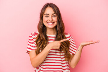 Young caucasian woman isolated on pink background excited holding a copy space on palm.